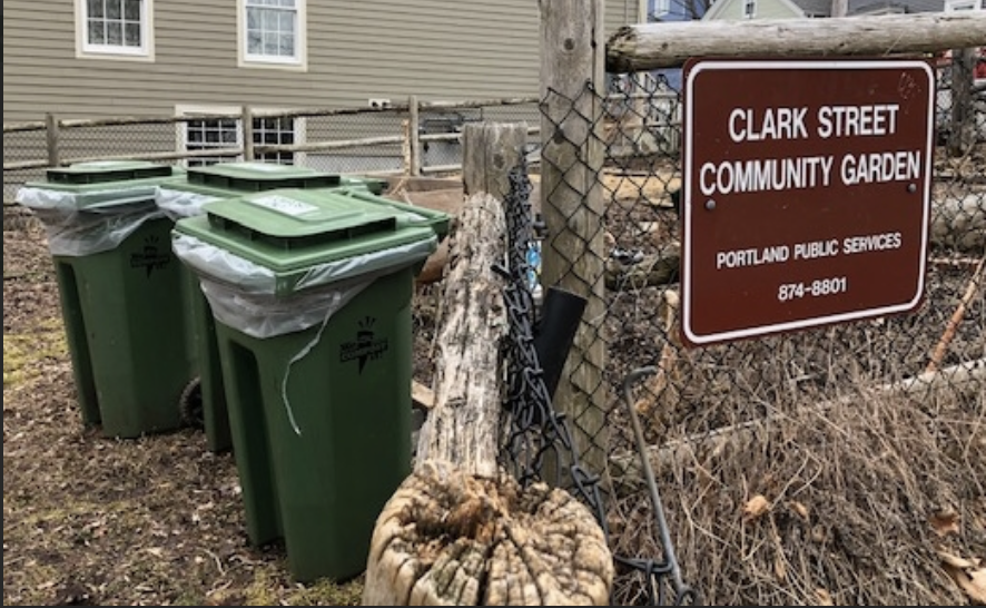 Two compost bins next to a community garden